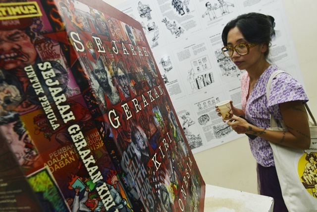 Seorang perempuan melihat replika buku bertajuk Sejarah Gerakan Kiri Untuk Pemula dalam Belok Kiri.Fest di Kantor LBH, Jakarta, Minggu (28/2)